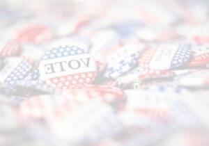 Close up photo of red, white and blue elections day buttons that read: VOTE